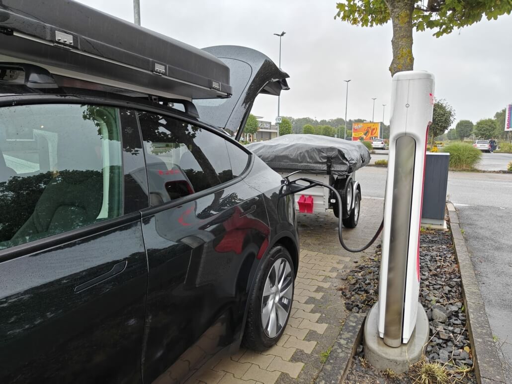 Tesla Model Y met daktent en vouwwagen op vakantie